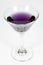 Halloween inspired purple color cocktail in a clear glass sitting on a white table waiting to be enjoyed.