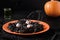 Halloween Italian black pasta decorated funny spiders in orange plate on black.