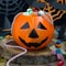Halloween Jack o Lantern bucket overflowing with candy, spooky Halloween decorations on background, square format