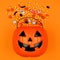 Halloween Jack o Lantern bucket with spilling candy, top view on an orange background