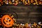 Halloween Jack o Lantern pail with double border of spilling candy over dark wood