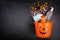 Halloween Jack o Lantern pail with spilling candy and COVID 19 prevention supplies over a black background