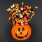 Halloween Jack o Lantern pail with spilling candy, top view on a black background