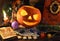 Halloween Jack O Lantern Pumpkin with grimoire book, tarot card Devil and runes on witch table