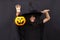 Halloween kid raises his hands up holding jack o lantern and makes faces to scare and get sweets. Child in black