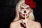 Halloween Make-Up Style. Blond Model Wear Sugar Skull Makeup with Red Roses. Santa Muerte Concept. Silence Gesture
