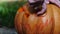 Halloween. Man hands carves a face in a pumpkin to make a jack o`lantern.