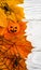 Halloween objects on white wooden table, vertical top view of fall maple leaves