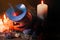 Halloween orange pumpkin with carved face. Scary pumpkin with candles and a purple witch hat