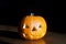 Halloween orange pumpkin head at dark background. Jack o Lantern photo with toothy scary face and shadow