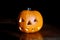 Halloween orange pumpkin head at dark background. Jack o Lantern photo with toothy scary face and shadow