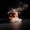 Halloween, orange pumpkin with a scary luminous face on a dark background. Thick gray smoke comes out and spreads across