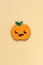 Halloween party accessory, shiny pumpkin with cute creepy faces. Pastel yellow background, place for text. Holiday flat lay.