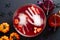 Halloween party concept. Bowl with bloody drink, frozen hands, strawberries and halloween decorations on dark background. Flat lay