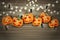 Halloween party illustration design with creepy pumpkin faces, haning lights, and spiders over brown wooden board background.