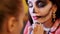 Halloween party, make-up artist draws a terrible makeup on the face of a brunette woman for a Halloween party. in the