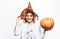 Halloween party. Wizard girl in witch hat with pumpkin. Autumn holiday. 31 October.