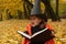 A Halloween photo of a little girl representing a wicked witch dressed in black and orange and holding a magic book