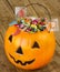 Halloween plastic pumpkin filled with candy on wooden table - 1