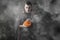 Halloween portrait Caucasian white man holding pumpkin dressed and makeup stylised for vampire on dark smoky background