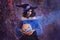 Halloween portrait fantasy woman witch. Girl sorceress in vintage purple costume medieval dress, tall cone hat. Magician