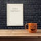 Halloween poster mock up template. Coffee cup as jack o lantern pumpkin on wooden table over black brick wall.