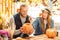 Halloween Preparaton Concept. Young couple sitting at table outdoors making jack-o`-lantern painting face on pumpkin