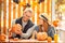 Halloween Preparaton Concept. Young couple sitting at table outdoors man showing jack-o`-lantern to woman happy