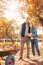 Halloween Preparaton Concept. Young couple standing at garden with pumpkins looking at cart full of harvest smiling