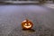 Halloween pumpkin on the asphalt on a deserted city street at night. Blurry colored city lights and old buildings