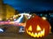 Halloween pumpkin on the background of the night city. Buildings and streaks of light from cars passing along the road
