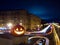 Halloween pumpkin on the background of the night city. Buildings and streaks of light from cars passing along the road