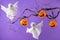 Halloween pumpkin buckets for candies and white ghosts over purple background. Halloween party concept. Funny holiday decorations