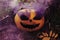 Halloween Pumpkin with a carved scary muzzle and purple smoke coming from the eye sockets.