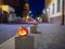 Halloween pumpkin on a deserted city street at night. Blurry colored city lights and old high-rise buildings