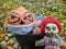 Halloween pumpkin in a disposable mask along with a gang of scary toys against a background of autumn foliage