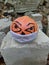 halloween pumpkin in a disposable mask on a background of old stones