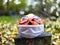 Halloween pumpkin in disposable mask on blurred background of autumn and colored leaves