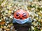 Halloween pumpkin in disposable mask on blurred background of autumn and colored leaves