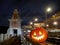 Halloween pumpkin with a glowing grimace at night on the railway bridge. In the background there are rails and blurry streaks of