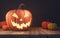 Halloween pumpkin head jack lantern on wooden planks and black background, spooky night