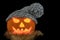 Halloween Pumpkin with Knitted Hat and Scarf on a Black Background