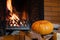 Halloween pumpkin lies on birch wood in front of a blazing fireplace. Mystical holiday Halloween.