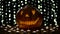 Halloween pumpkin lights inside with flame on a black bokeh background with lighted candles