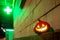 Halloween pumpkin at night against the background of a pharmacy cross glowing in the dark