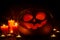 Halloween pumpkin with scary face and candles on wooden background
