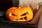 Halloween pumpkin with spooky face. Halloween symbol in front of street cafe entrance sunny autumn day. Happy Halloween day. Close