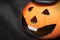 Halloween pumpkin with spooky smiling face on dark black background wiyh copy space