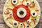 Halloween scary food funny eye monster pizza with mozzarella and tomato sauce