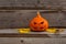 halloween scary pumpkin with eyes and mouth and yellow leaves on wooden background. Autumn Pumpkin